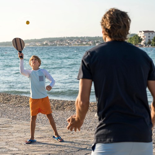Father and son play beach tennis on the beach